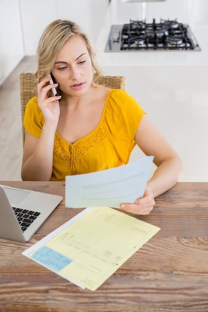 A person organising receipts and documents in a folder, with a laptop in the background displaying a tax return form.