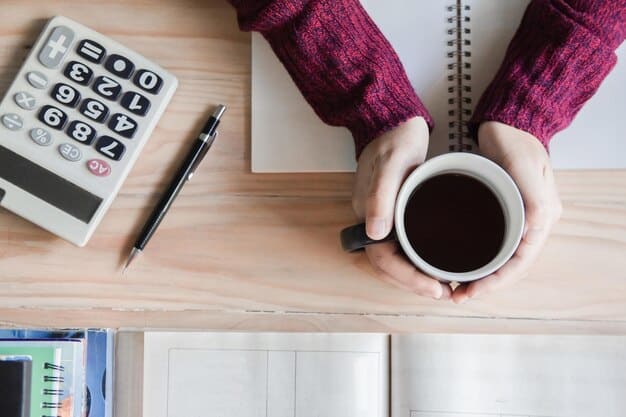A close-up shot of a person's hands using a calculator to determine loan repayment amounts, with various financial documents and a coffee mug on the table.