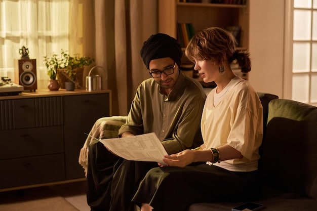 Two people sitting side-by-side on a couch, looking at papers and discussing their budget. The setting is a cozy living room, and they are holding coffee mugs.