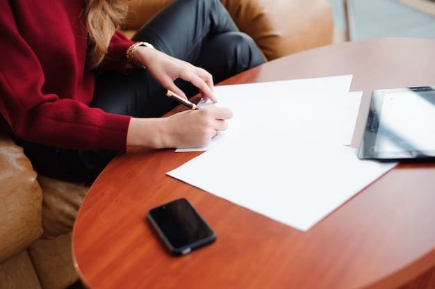 A person filling out a paper application form for government benefits at a desk, with various documents and a pen in hand.