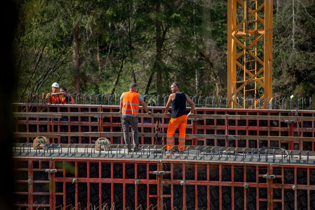 Construction workers on a bridge construction site, wearing safety gear and operating heavy machinery, highlighting job creation in the infrastructure sector.